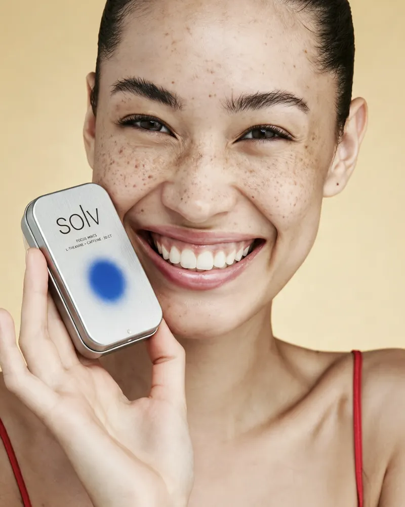 Carrusel: mujer sonriendo con un producto de cuidado de la piel